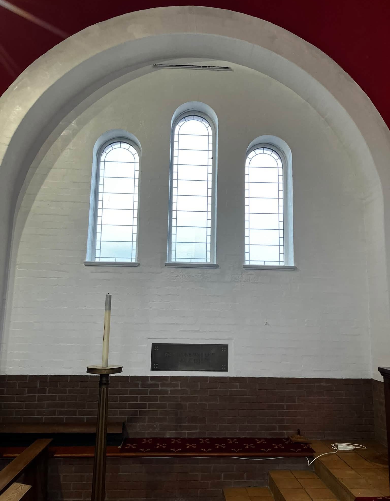 Three arched windows in a freshly painted white church wall