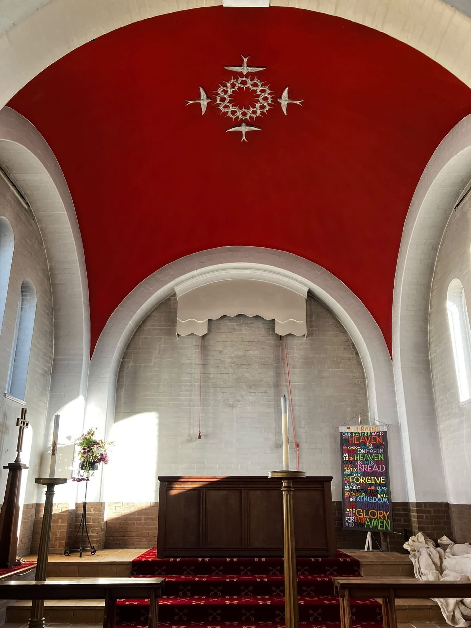 Altar end of a church under a red vault, walls painted white