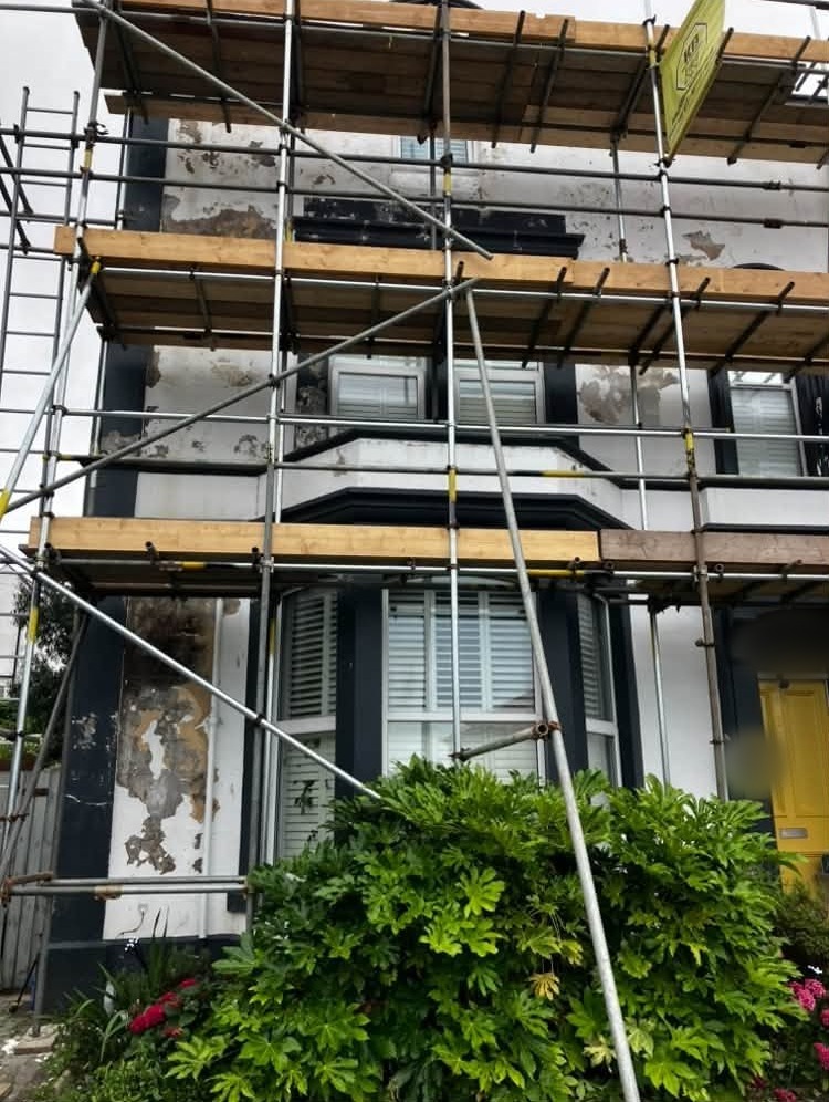 Victorian house front under scaffolding, old paint flaking, before decorating