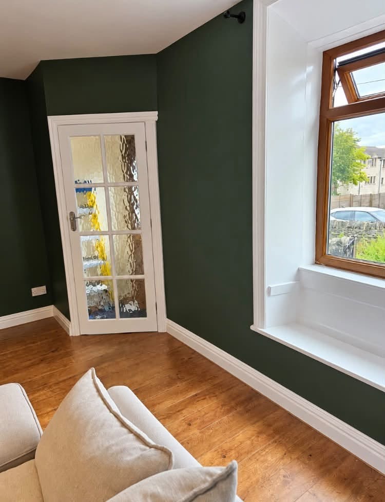 Lounge painted deep green with white woodwork and a glazed door
