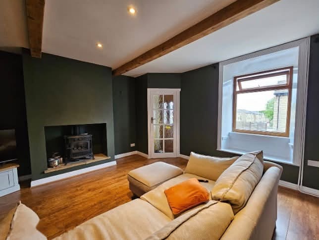 Dark green lounge with a wood burner and beams