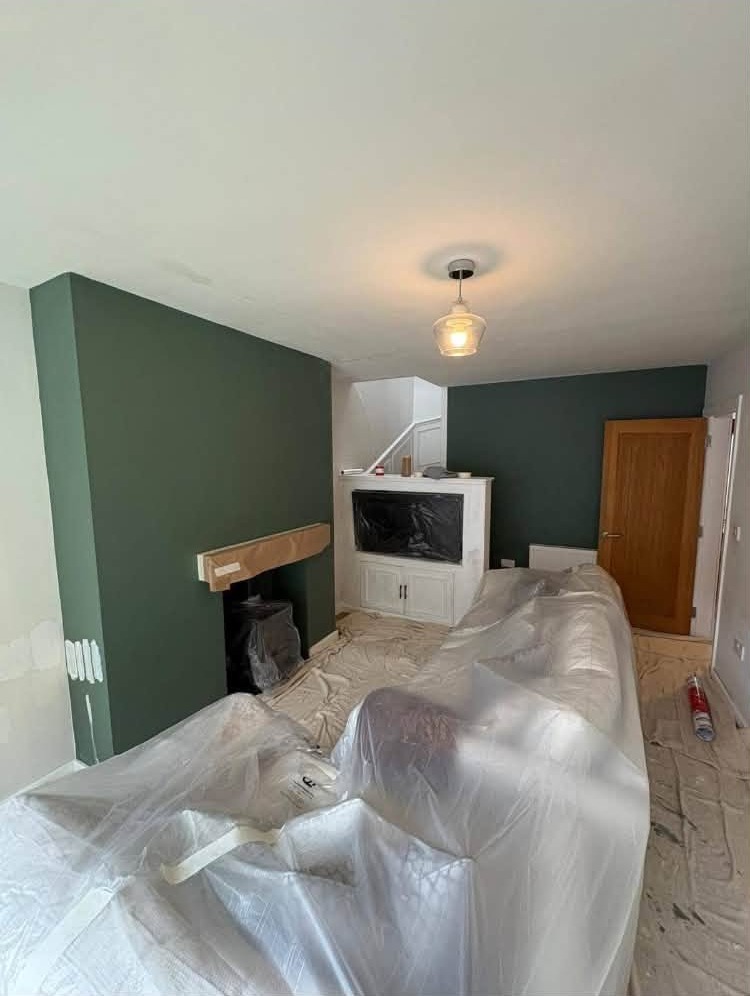 Lounge sheeted up with dust sheets while the chimney breast is painted green