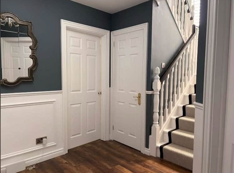 Hallway doors and the foot of the staircase, white woodwork against blue