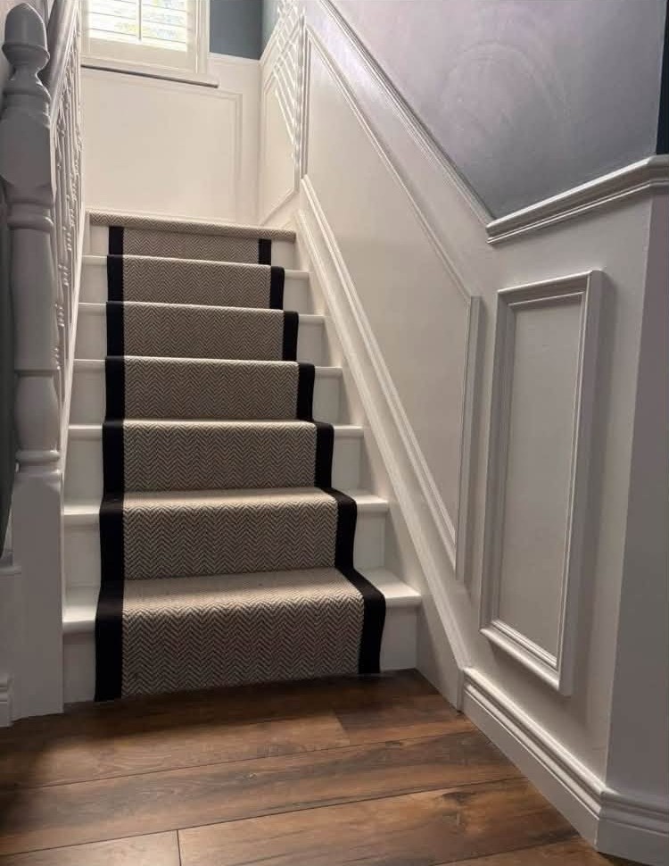 Staircase with a patterned runner edged in black, white panelling alongside