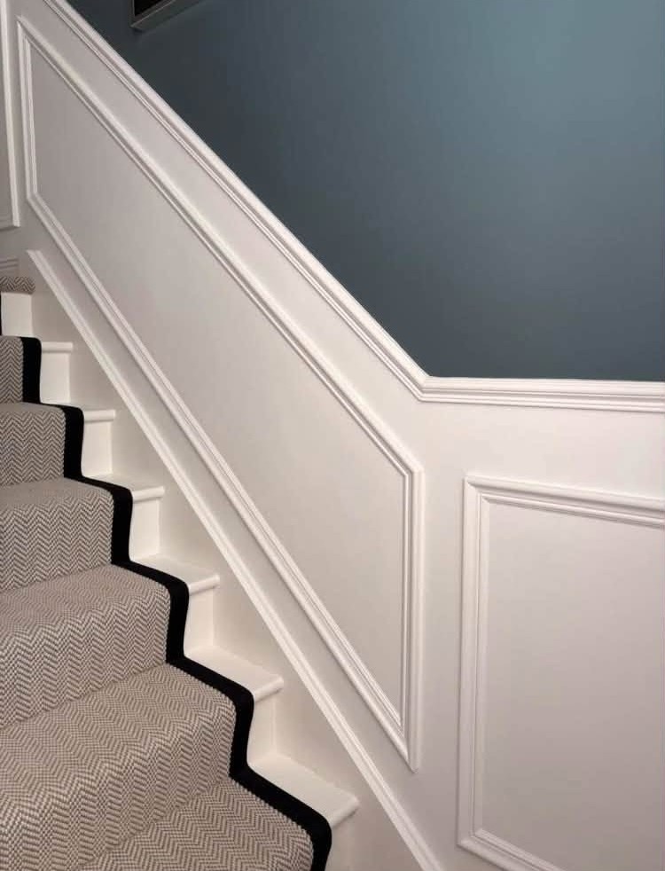 Close up of white stair panelling rising beside the runner