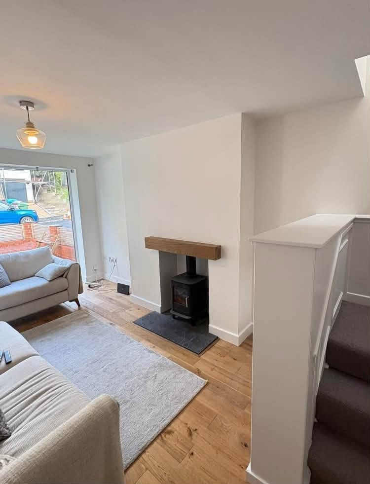 White lounge with an oak mantel and a wood burner