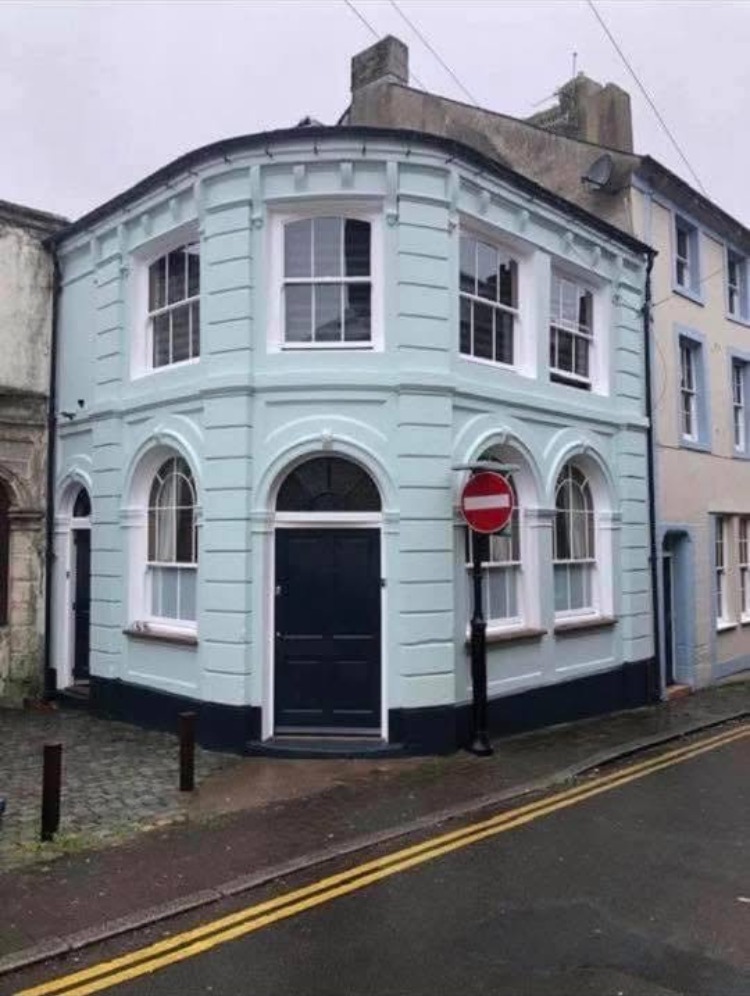 Corner building repainted pale blue with dark doors and white window surrounds